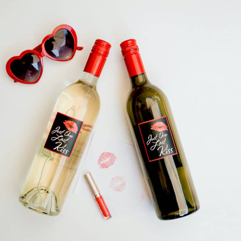 two bottle of wine next to sunglasses shaped like hearts and liptstick and kisses of lipstick