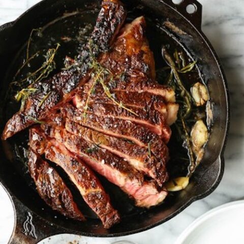 rosemary garlic ribeye steak in a pan on a marble counter