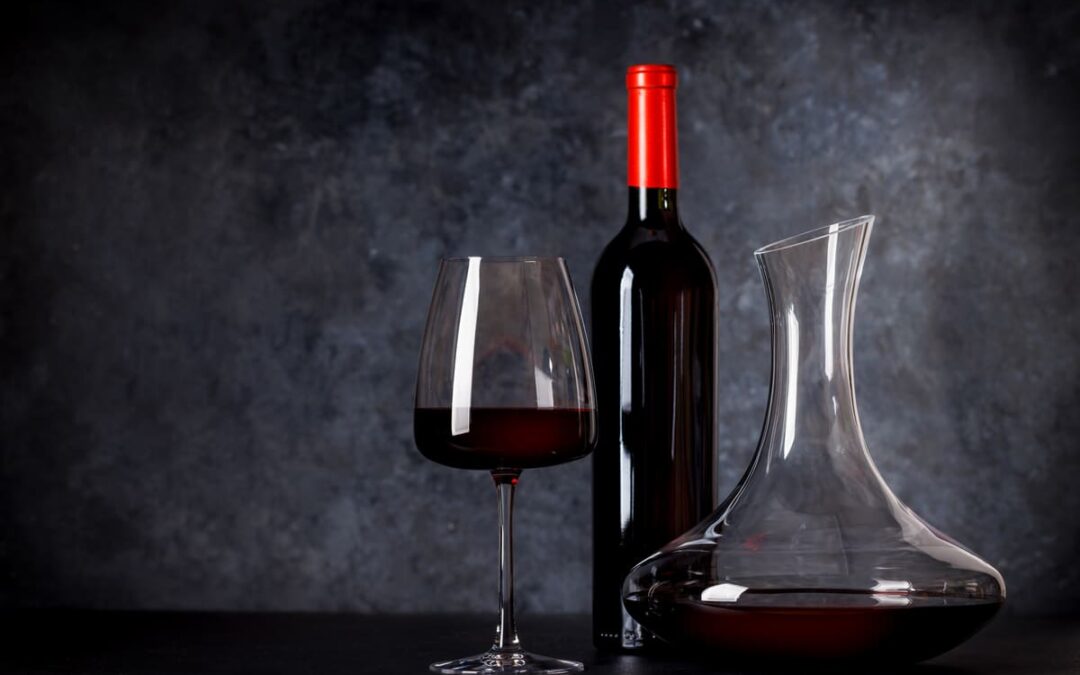 Decanter, wine glass and bottle against a stone background