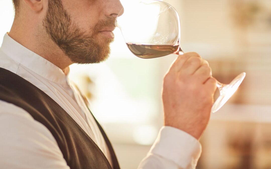 guy smelling red wine in wine glass