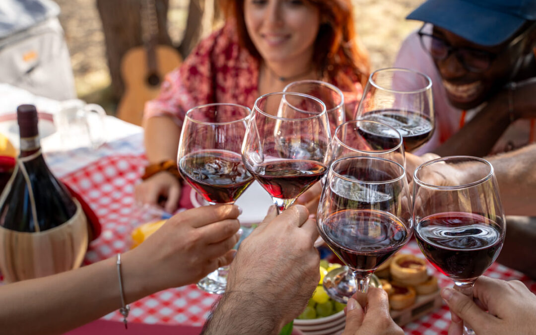 group of red wine glasses being held together