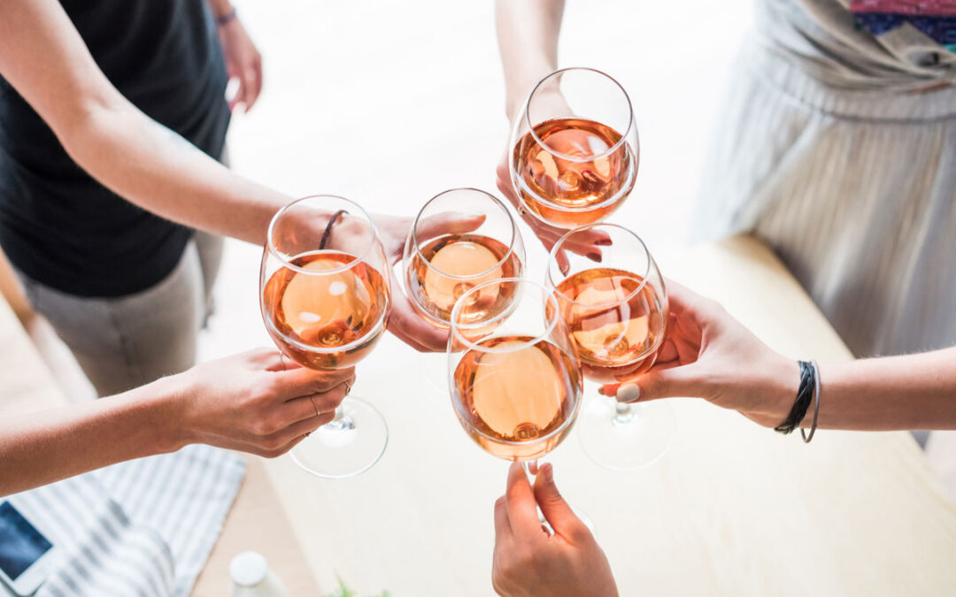 People cheersing rose glasses at a tasting